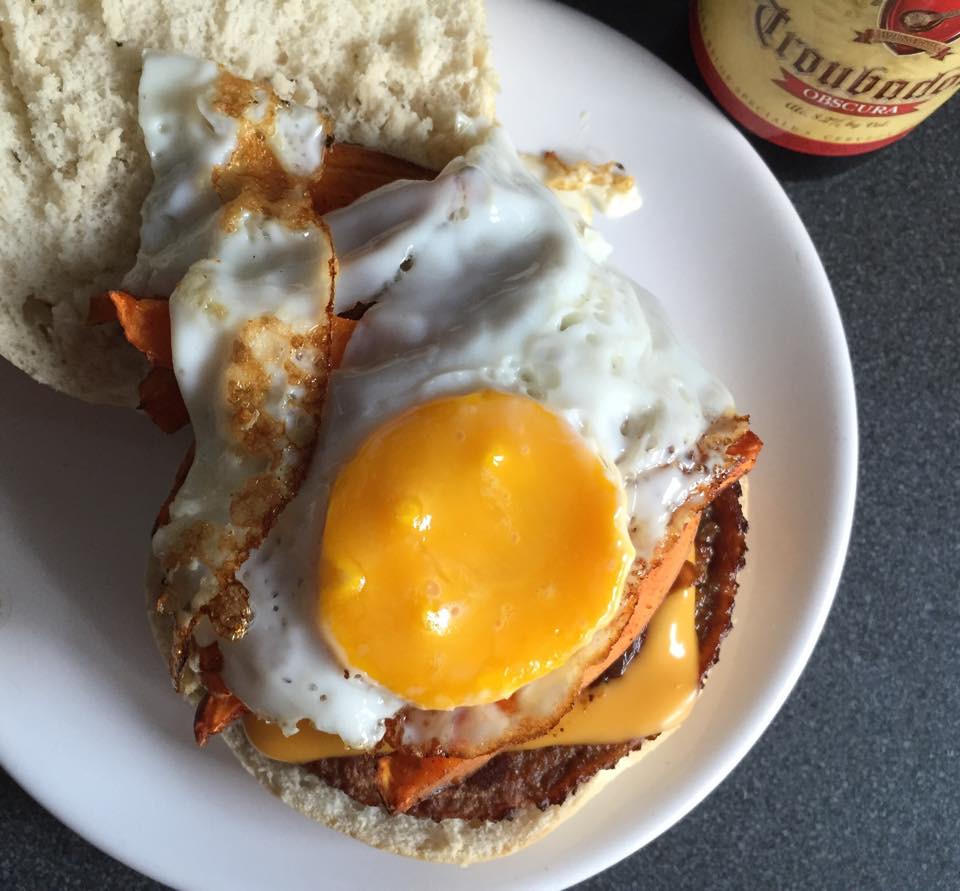 Burger vegetarian cu ou prajit, cartofi dulci si ceapa caramelizata in bere